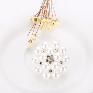 Detailed view of white pearl flower brooch with rhinestone center on a ceramic plate