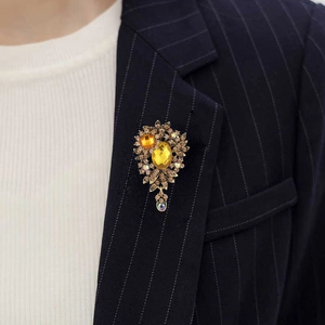 Detailed view of vintage gold flower brooch with amber crystals on a blue navy suit lapel