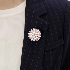 Detailed view of floral pearl brooch with rhinestones worn on a black striped suit blazer