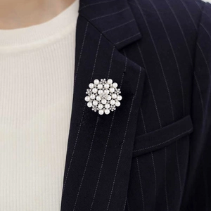 Detail of floral brooch with white pearls and sparkling rhinestones on a navy suit lapel