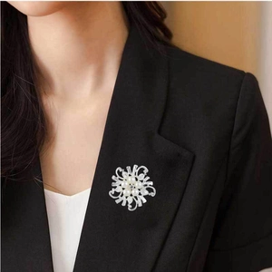 Elegant floral brooch with pearls and zircons pinned on a black suit lapel detail