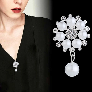 Detail of floral pearl brooch with rhinestones and dangling drop on black fabric