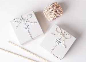 Close-up of white gift boxes with black-white and gold-white cotton twine and labels