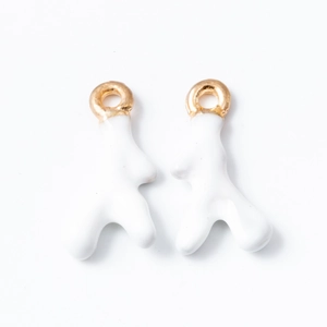 Macro detail of abstract white enamel human-shaped earrings with gold metal hooks