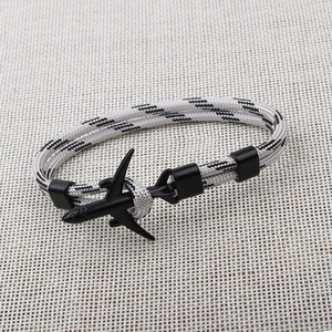 Detail of the black airplane charm with black and white braided paracord strap on fabric