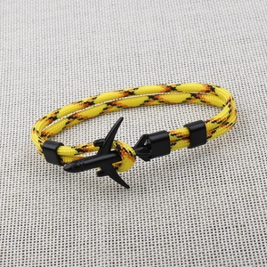 Detail of yellow and black woven 550 paracord bracelet with black airplane pendant charm