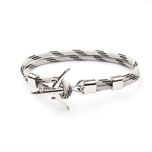 Detailed close-up of a silver airplane charm on a black and white nautical cord bracelet