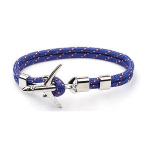 Detailed macro view of woven blue rope bracelet with silver airplane charm