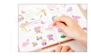Close-up of translucent gold-stamped crystal stickers applied on a notebook page