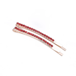 Set of two rose gold hair clips with elegant red rhinestones on a white background