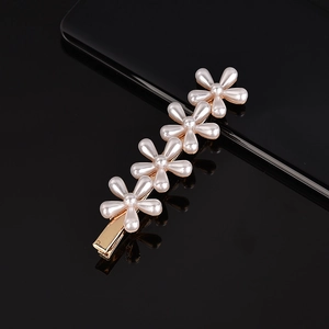 Macro detail of hand-woven pearl hair clip with five white flowers on golden base