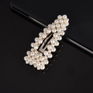 Macro shot of rectangular pearl hair clip with white pearls on a sleek black background