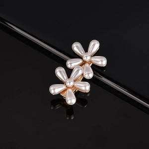 Close-up of elegant pearl flower hair clips with gold metal base on reflective black surface