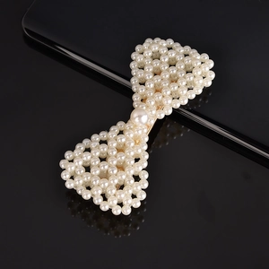 Macro detail of hand-woven pearl bow hairpin on a golden metallic base for women