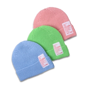 Three colorful rib-knit beanies in pink, green, and blue with stylish textile labels