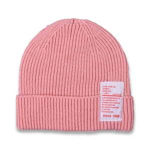 Detail of pink knit beanie showing rib-knit texture and sewn-on decorative white patch
