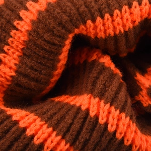 Gros plan détaillé du tissu en maille côtelée avec motif à rayures marron et orange