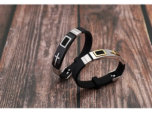 Close-up of adjustable silicone cross bracelets with silver and gold metal clasps on wood