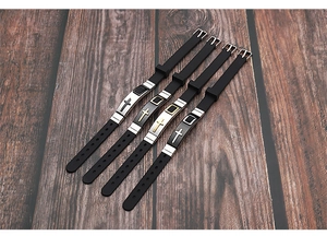 Detail of adjustable black silicone wristbands with gold and silver cross and square charms