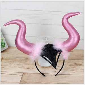 Detailed close-up of a pink devil horn headband with glitter scales and feather trim