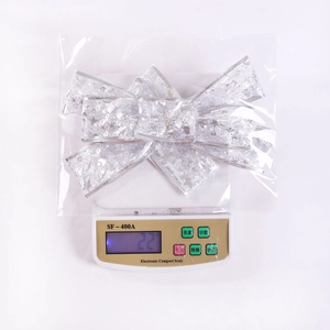 Close-up of white mesh Christmas bow with silver snowflakes on a weighing scale
