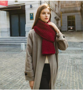 Close-up of thick deep red chunky knit scarf on model in autumn street setting