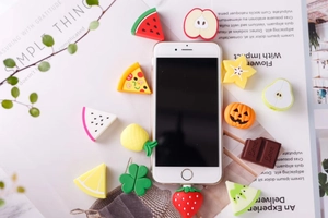 Close-up of various silicone fruit and food shaped cable protectors for phone chargers