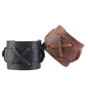 Détail de bracelets punk larges en cuir noir et marron avec lacets croisés décoratifs