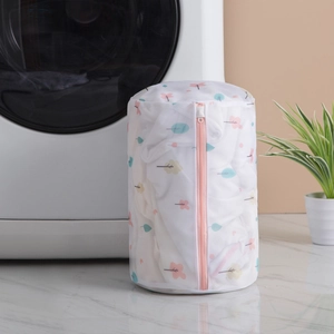 Thick fine mesh laundry bag with tree pattern and pink zipper by a washing machine