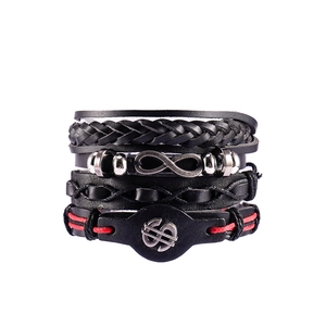 Detailed view of four black leather bracelets with metal infinity and dollar signs
