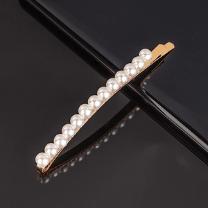 Detail of 12 elegant white pearls set on a golden metal minimalist hair clip