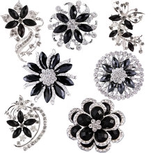 Set of seven black and silver flower brooches with rhinestones on white background