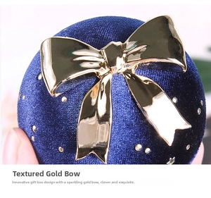 Macro detail of dark blue velvet jewelry box with glossy gold bow and star accents