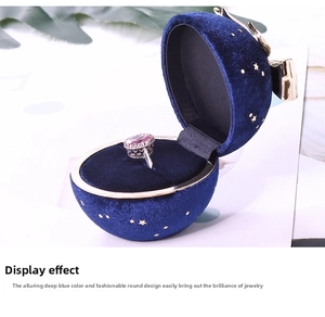 Macro view of blue velvet jewelry box with star patterns and pink gemstone ring