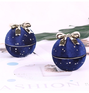Detailed view of spherical navy blue velvet jewelry box with gold bow and star accents