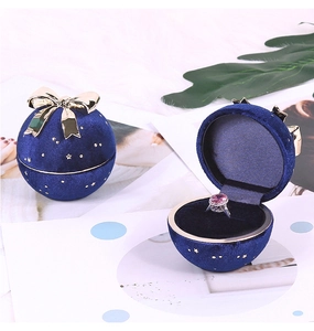 Detail of round navy velvet jewelry box with golden bow and star pattern finish