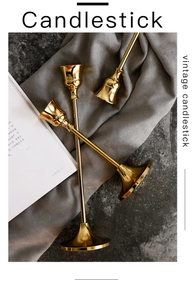 Detailed view of three vintage gold brass candle holders with long stems on grey stone