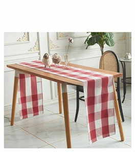 Detail van de rood-wit geruite tafelloper op een houten tafel in Scandinavische stijl