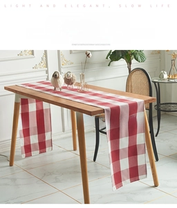 Detailopname van de rood-wit geblokte tafelloper op een houten tafel in Scandinavische stijl