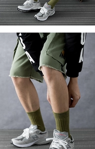 Detail of army green cargo shorts with raw edges and olive green ribbed cotton crew socks