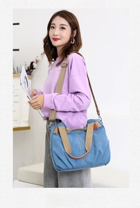 Blue canvas tote bag shown in a soft indoor setting with beige strap details