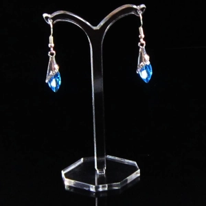 Macro view of blue crystal teardrop earrings hanging on a transparent acrylic T-stand