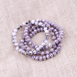 Detail of multi-layered amethyst crystal bead bracelets set on a neutral linen backdrop