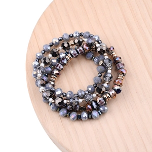 Detail of multi-layer natural amethyst and crystal beaded bracelet on a wood tray