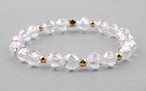 Detailed macro view of faceted clear crystal beads with gold-tone spacers on an elastic bracelet