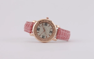 Detail of rose gold watch with crystal bezel, roman numerals and pink leather strap