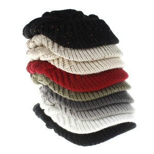 Vertical stack of assorted knit ponytail beanies showing thick cable stitch texture