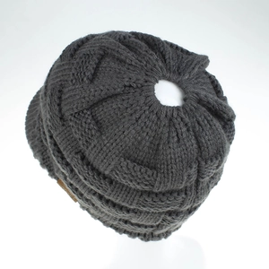 Detailed knit texture of dark grey ponytail beanie showing thick cable pattern weave
