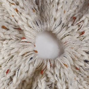 Macro detail of flecked yarn knit material featuring a functional ponytail hole design