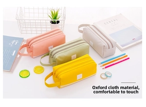 Detalle de cuatro estuches de tela Oxford de colores con cremallera triple y asa de mano